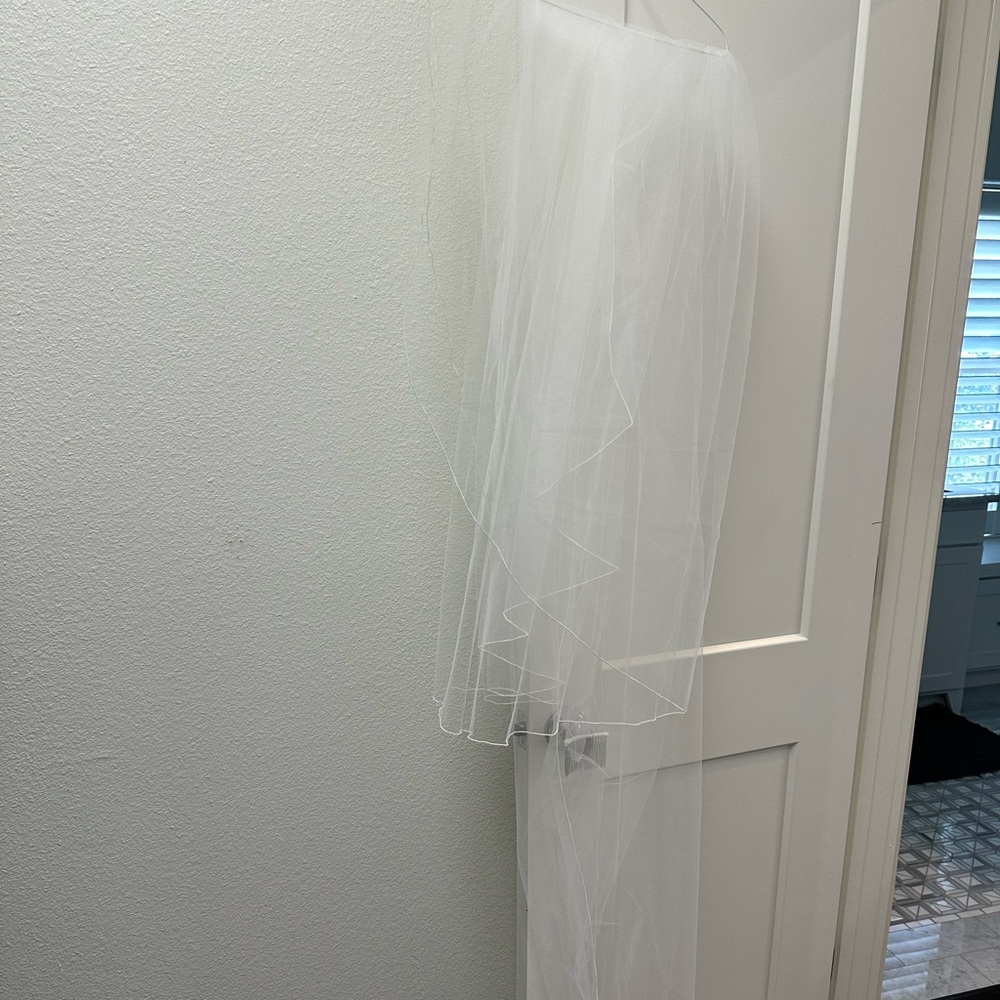 Includes long veil. Slight discoloring on lace at bottom of the dress.